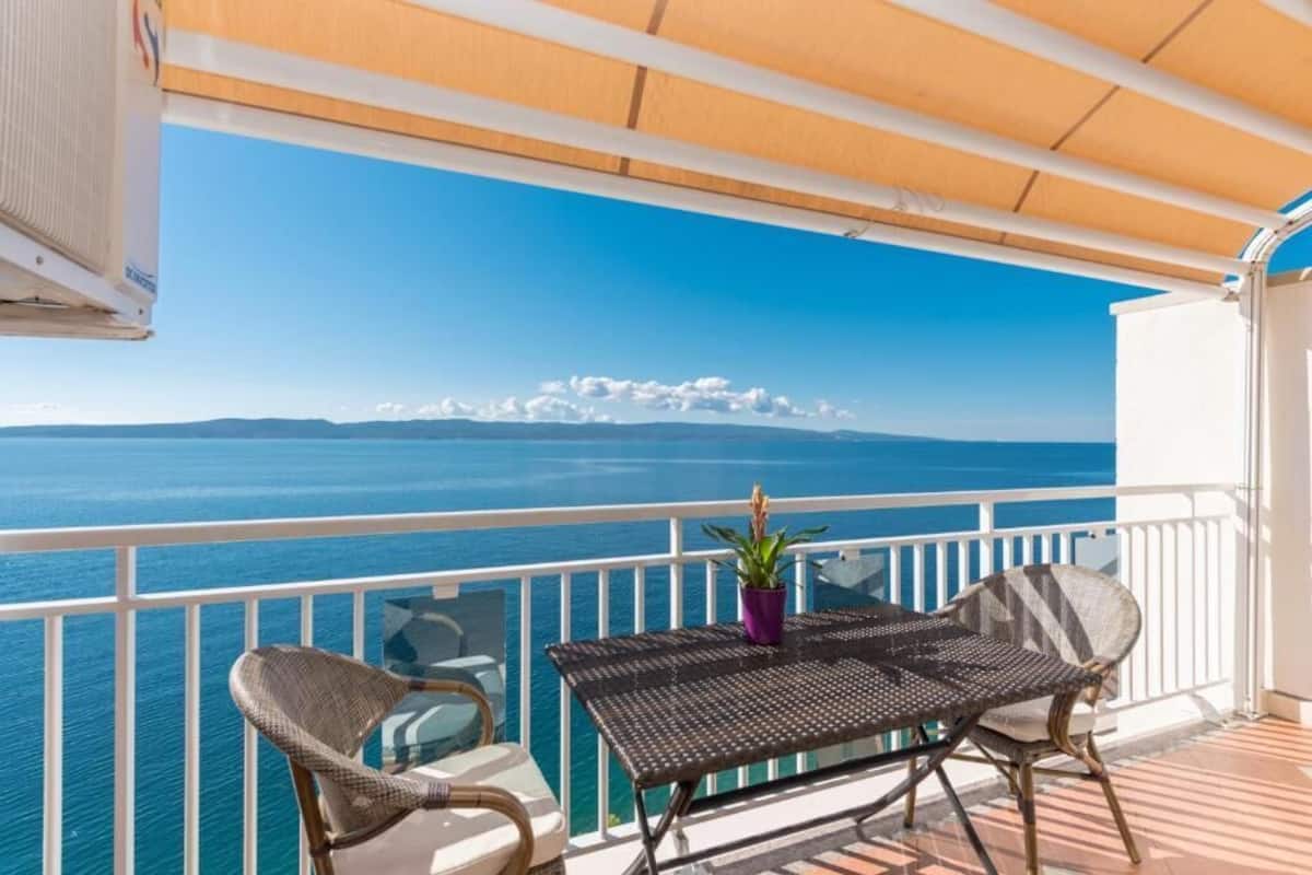 A balcony with a view of the sea and distant mountains.
