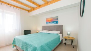 Une chambre à coucher avec un lit, un tableau représentant un coucher de soleil, une table de chevet et une chaise.