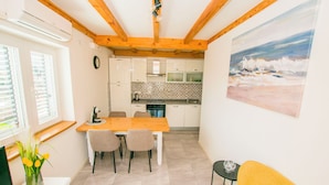 Une cuisine moderne avec des meubles blancs, une table à manger en bois et un canapé jaune.