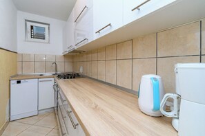 A kitchen with a built-in dishwasher, a stove, and a kettle. - Apartments Milan (Lopar)