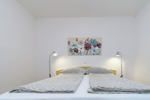 Ein Zimmer mit einem Bett, zwei Nachttischlampen und einem Blumenbild an der Wand.
