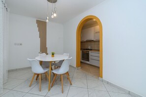 Un coin repas comprenant une table ronde, quatre chaises et un luminaire suspendu.