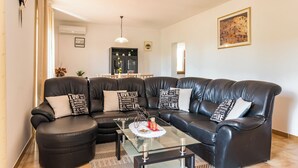 En moderne stue med en sort lædersofa i sektioner, et glasbord og dekorative puder.