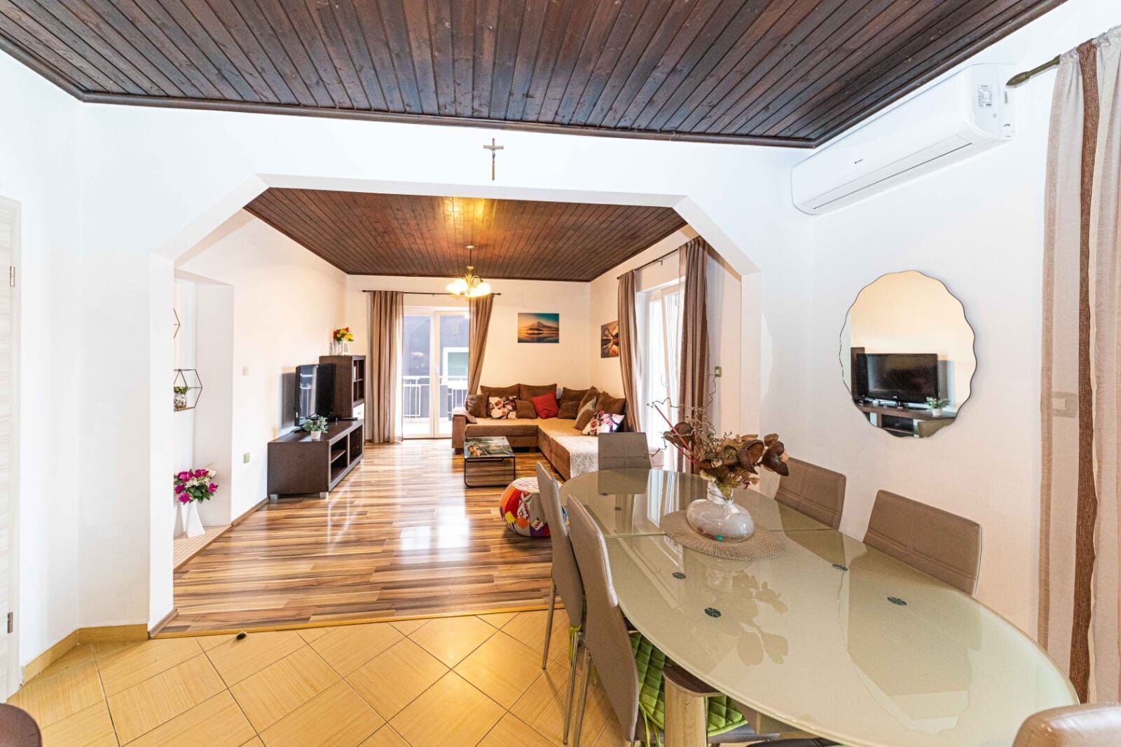 Una sala de estar moderna con techo de madera, una mesa de comedor de vidrio y un sofá.