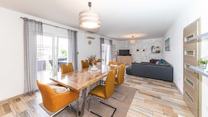 A modern living space with a dining area, a sofa, and a TV. - Apartments Piveta (Okrug)