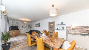 A modern living space with a dining area, kitchen, and entertainment area. - Apartments Piveta (Okrug)