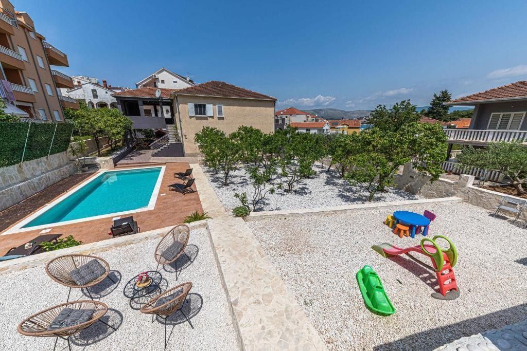 A pool area with lounge chairs, a children's play area, and a view of surrounding buildings.