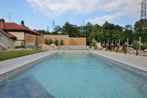 A rectangular swimming pool with clear blue water, surrounded by a concrete deck and a wooden fence. - House Midas (Matulji)
