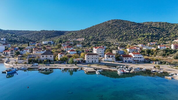 A coastal town with houses, a marina, and a hilly backdrop. - Apartment Anea (Marina)
