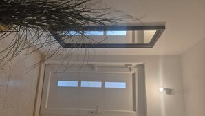 A modern interior with a skylight, a door with a handle, and a light fixture on the wall. - Apartment Anea (Marina)