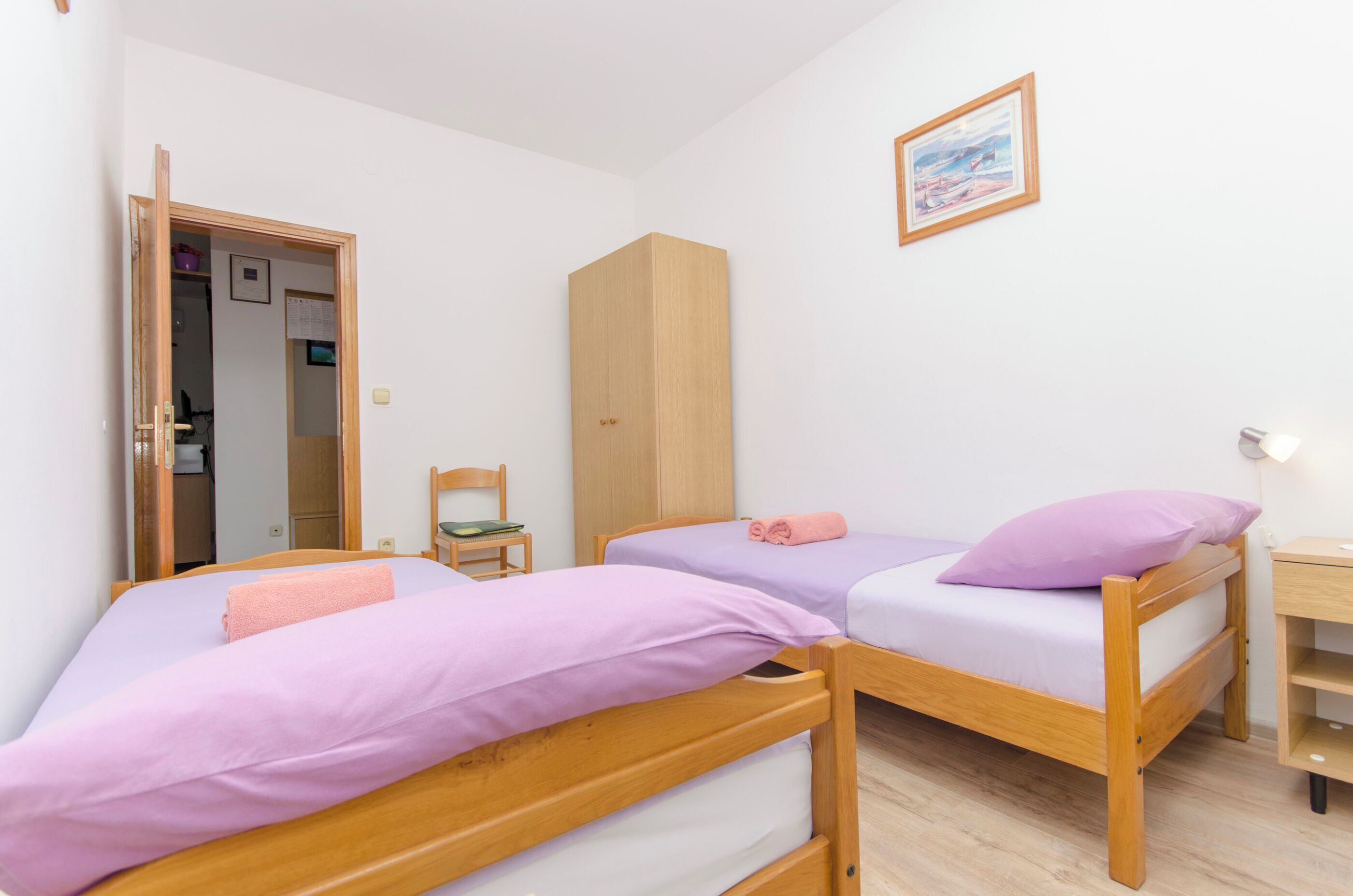Un dormitorio con dos camas literas de madera, un armario, una silla y un escritorio.