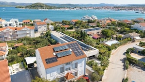 A coastal residential area with houses, a marina, and a large building with solar panels. - Apartments Nada (Murter-Kornati)