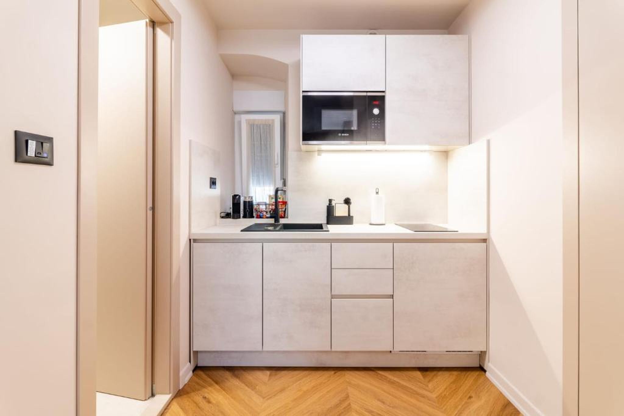 A compact kitchen with a microwave, a sink, and a countertop.