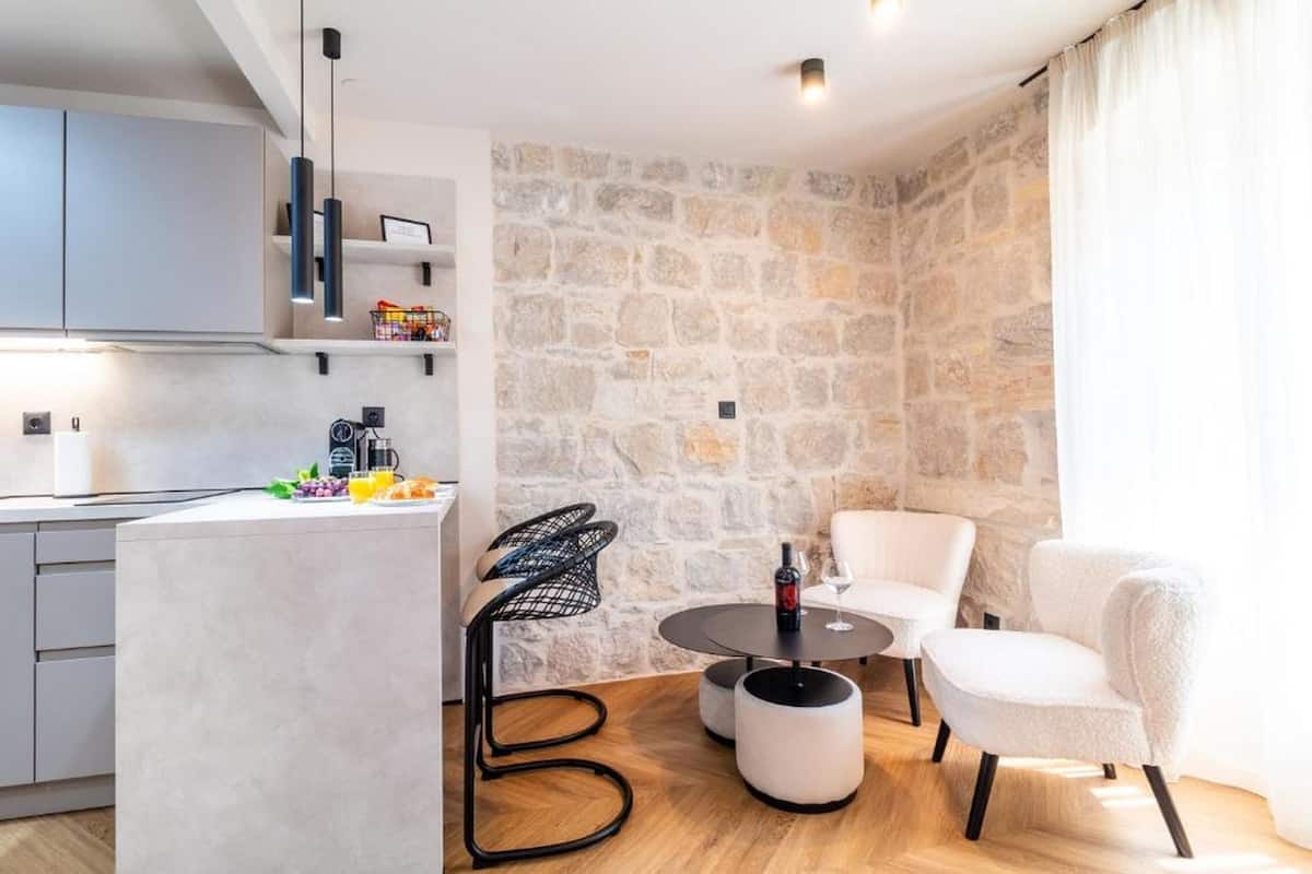 A modern kitchen with a stone wall, a dining area with a round table, and two chairs.