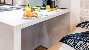 A modern kitchen with a central island, built-in appliances, and a stone accent wall. - Apartments Centre In Stone House (Split)