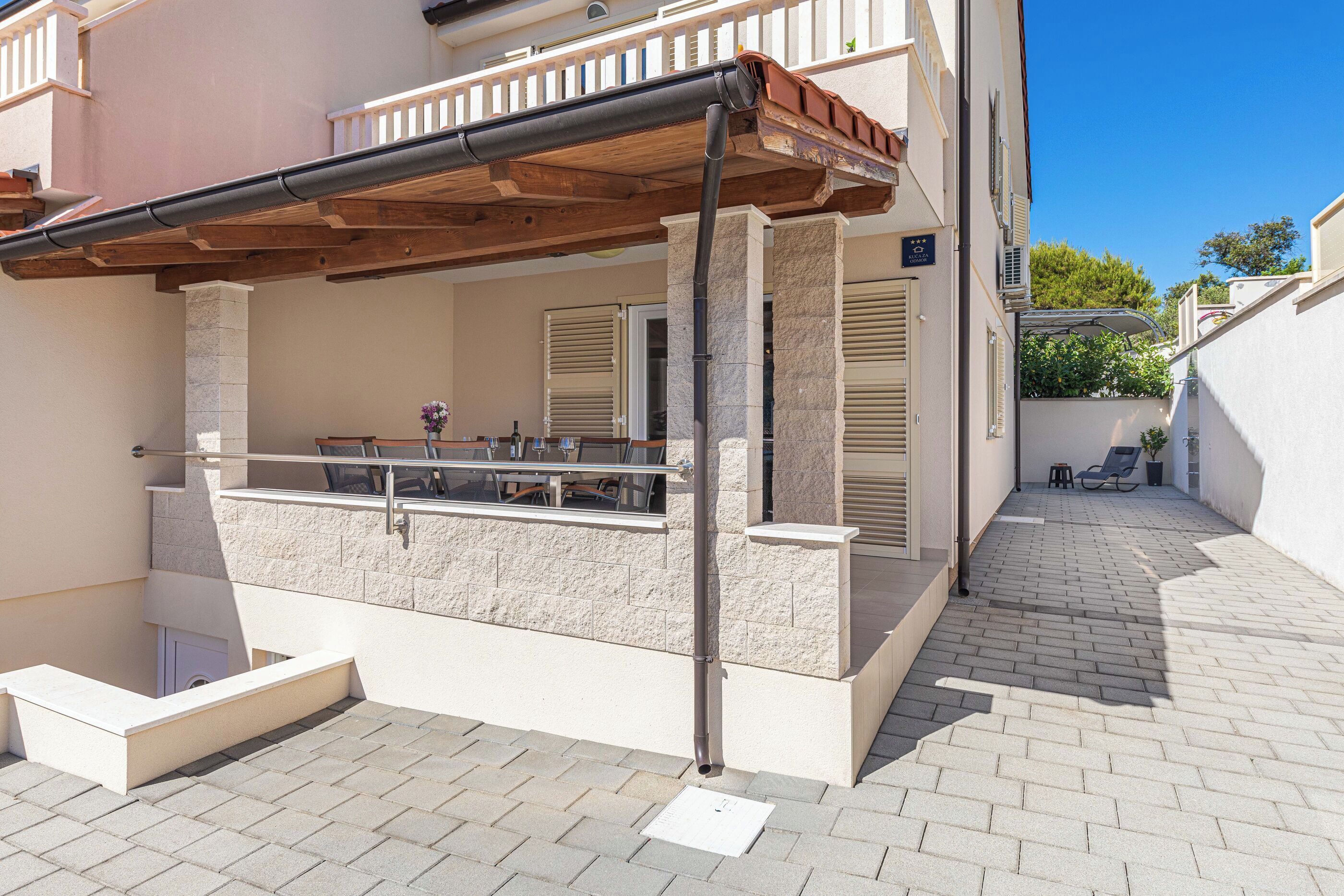 A covered outdoor seating area with stone pillars, a wooden pergola, and a view of the street.