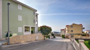 Un carrer residencial amb cases, una paret de pedra i un cel serè.