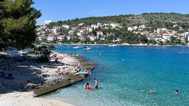 A coastal town with clear blue waters, sandy beaches, and a backdrop of colorful buildings. - Apartments Apartments -T and T (Okrug)