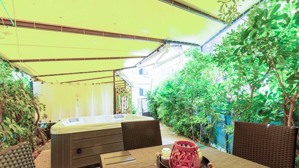 A hot tub under a yellow canopy, surrounded by greenery and wicker furniture. - Apartment Center With Jacuzzi (Split)