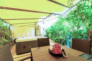 A hot tub under a yellow canopy, surrounded by greenery and wicker furniture. - Apartment Center With Jacuzzi (Split)