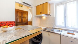 A compact kitchen with a built-in stove, a sink, and a window with curtains. - Apartment Center With Jacuzzi (Split)