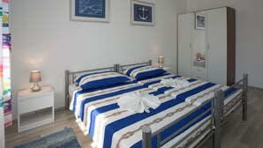 Ett hotellrum med två sängar, en garderob, ett nattduksbord med en lampa och två inramade tavlor på väggen.