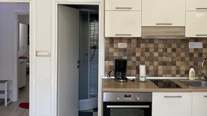 Ett modernt kök med vita skåp, en kaffebryggare och en klocka på väggen.