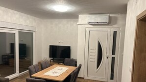 A dining area with a table, chairs, and a television. - House Sunshine (Pasman)