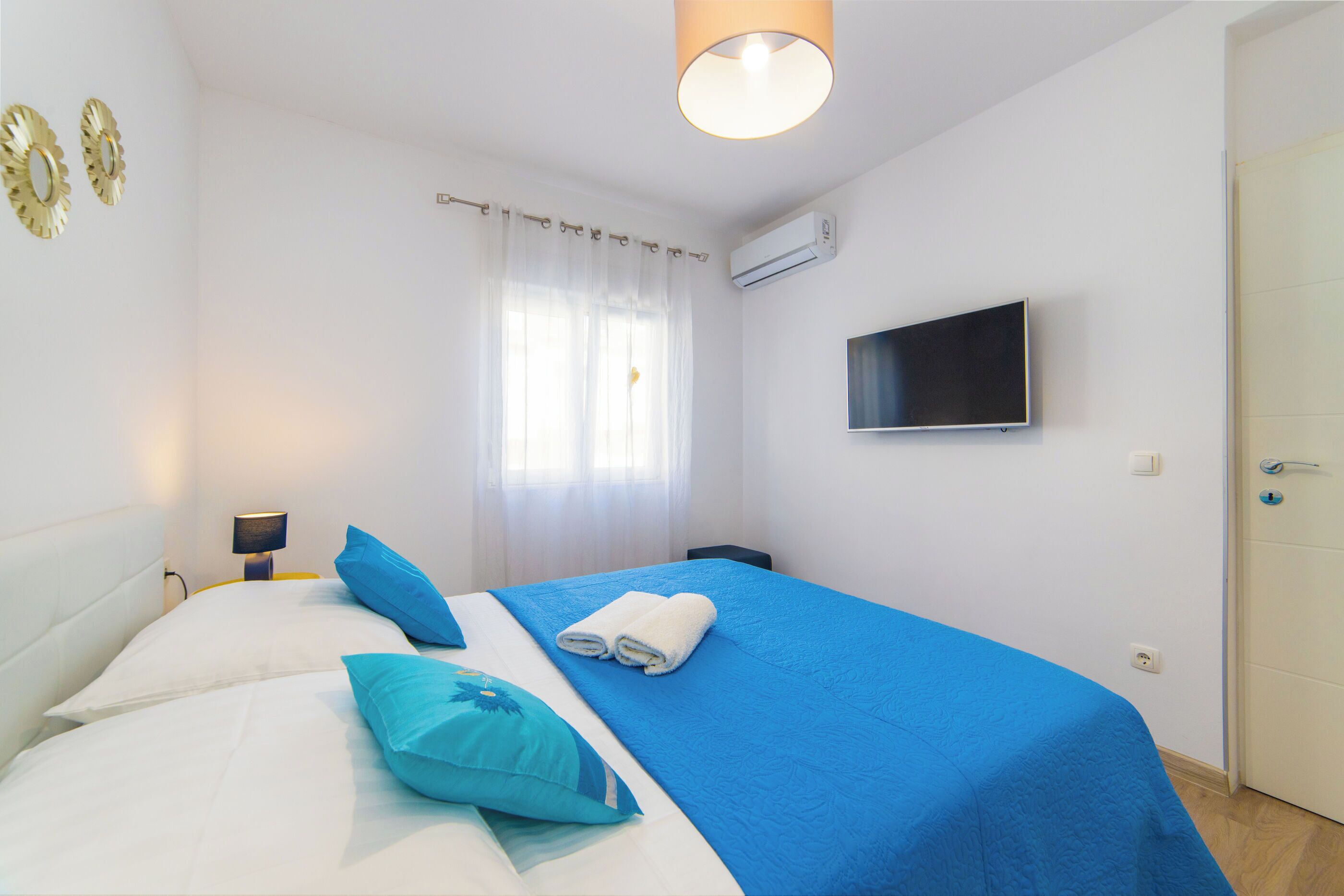 A hotel room with a bed, a TV, and a window with curtains.