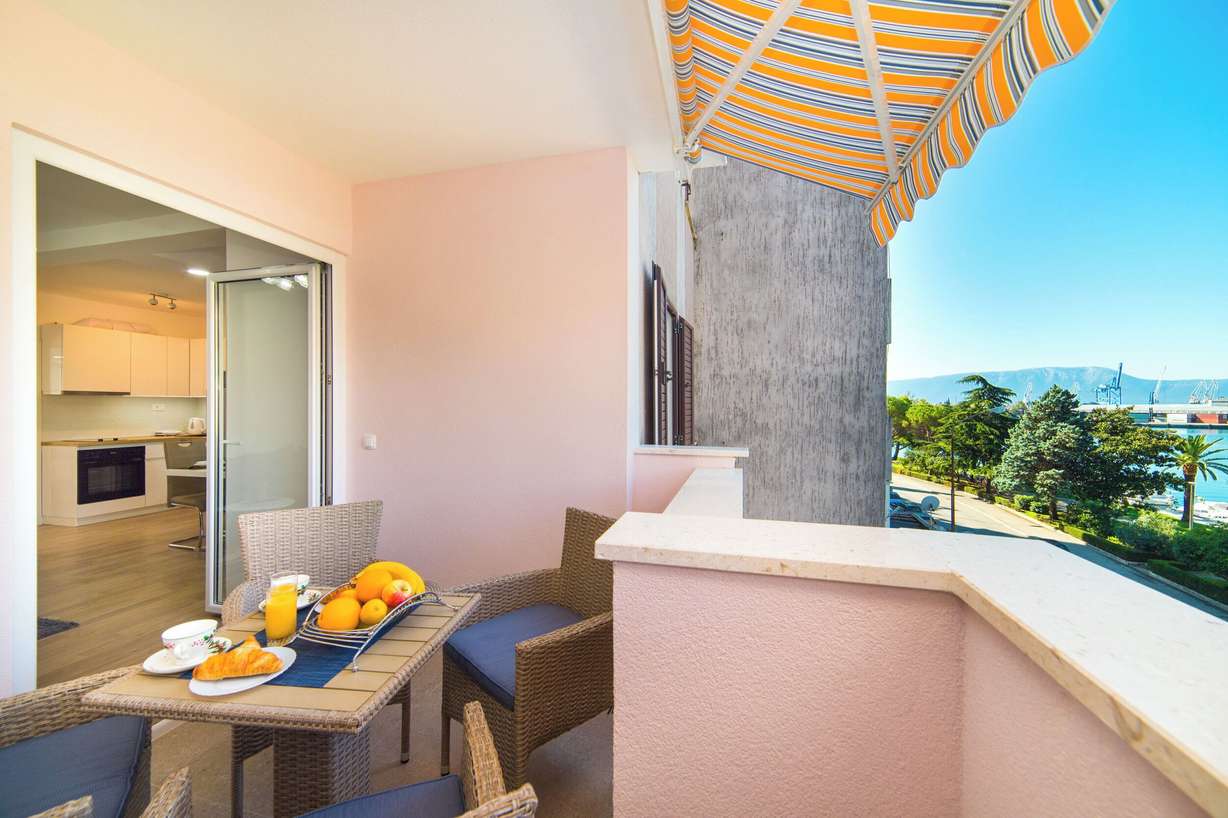 A balcony with a table set for breakfast, a wicker chair, and a view of the cityscape.