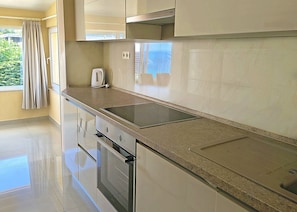A modern kitchen with a stainless steel stove, a built-in oven, and a granite countertop. - Apartments Fenix (Primosten)