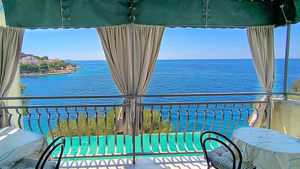 Ein Balkon mit Meerblick, zwei Stühle und ein Tisch.