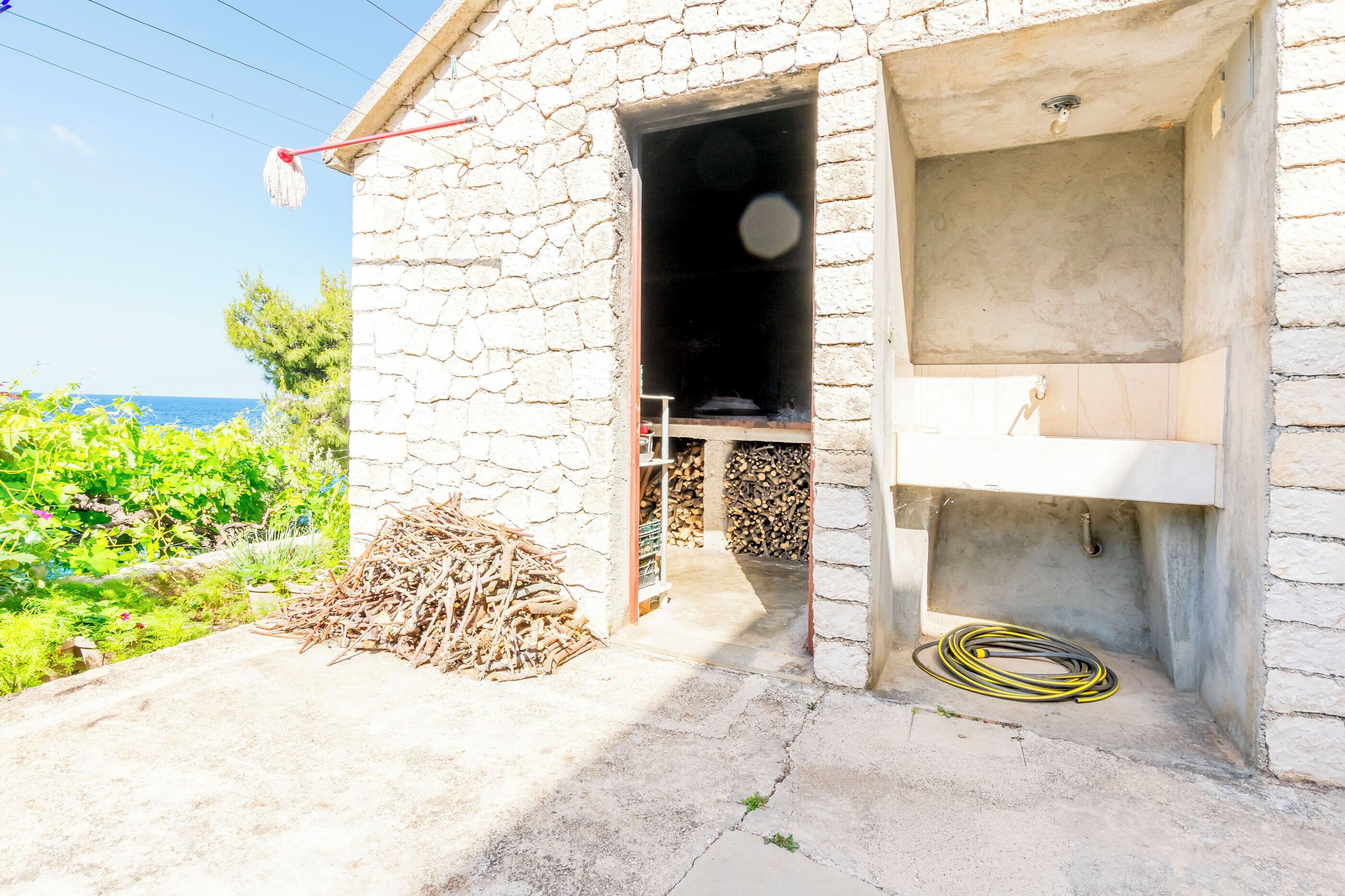 A stone building with a small open doorway leading to a room with a sink and a hose.