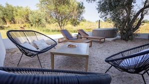 Eine Terrassenfläche mit Korbstühlen, einem Tisch und einem fest installierten Heizgerät.