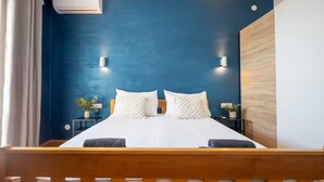 Ein Schlafzimmer mit einem Holzbettgestell, weißer Bettwäsche und einer blauen Akzentwand.