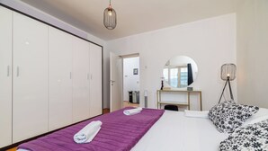 Ein Hotelzimmer mit Bett, Schrank, Schreibtisch mit Spiegel und Nachttisch mit Lampe.