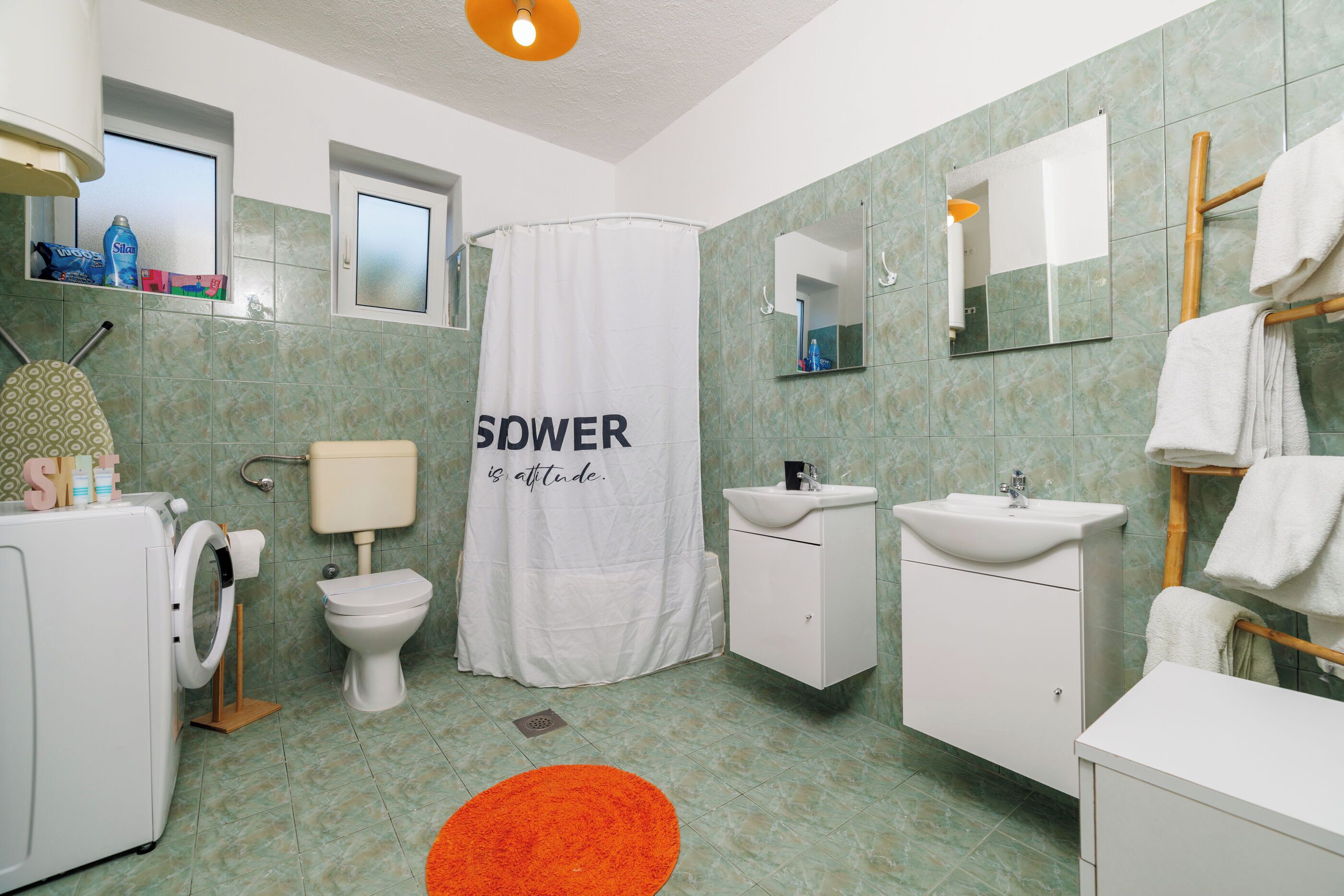 A bathroom with a shower curtain, toilet, sink, and a mirror.