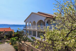 A two-story building with a balcony, arched windows, and a view of the sea. - Apartment Mare (Novi Vinodolski)