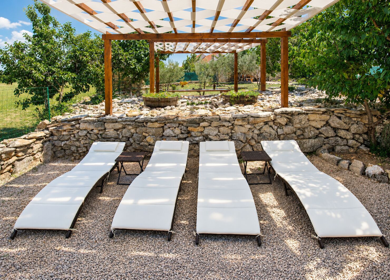 A covered outdoor seating area with stone walls and a pergola structure.