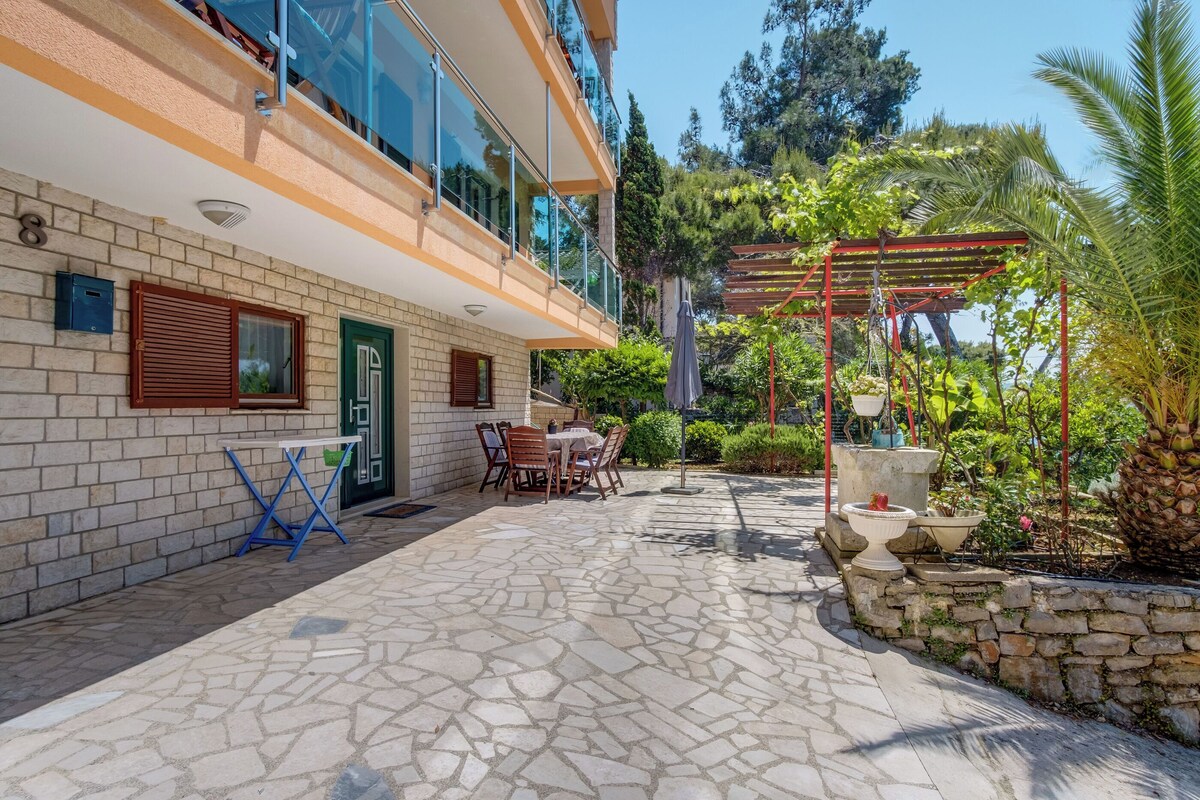 Um edifício moderno com um alpendre de pedra, área de estar ao ar livre e pérgola.