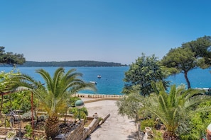 Vista costeira com um caminho que leva a uma praia, cercada por vegetação e com vista para o mar.