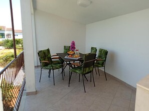 A balcony with a table and chairs, a flower vase, and a view of the outside. - Apartment Rosa (Supetar)
