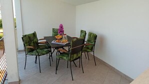 Ein Essbereich mit einem runden Tisch und sechs Stühlen, jeder mit einem grün gemusterten Sitzkissen.