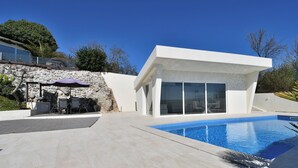 A modern house with a swimming pool, stone wall, and outdoor furniture. - House Luxury (Matulji)