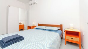 Ein Schlafzimmer mit einem Bett, Nachttischen, einer Lampe und einer Klimaanlage.