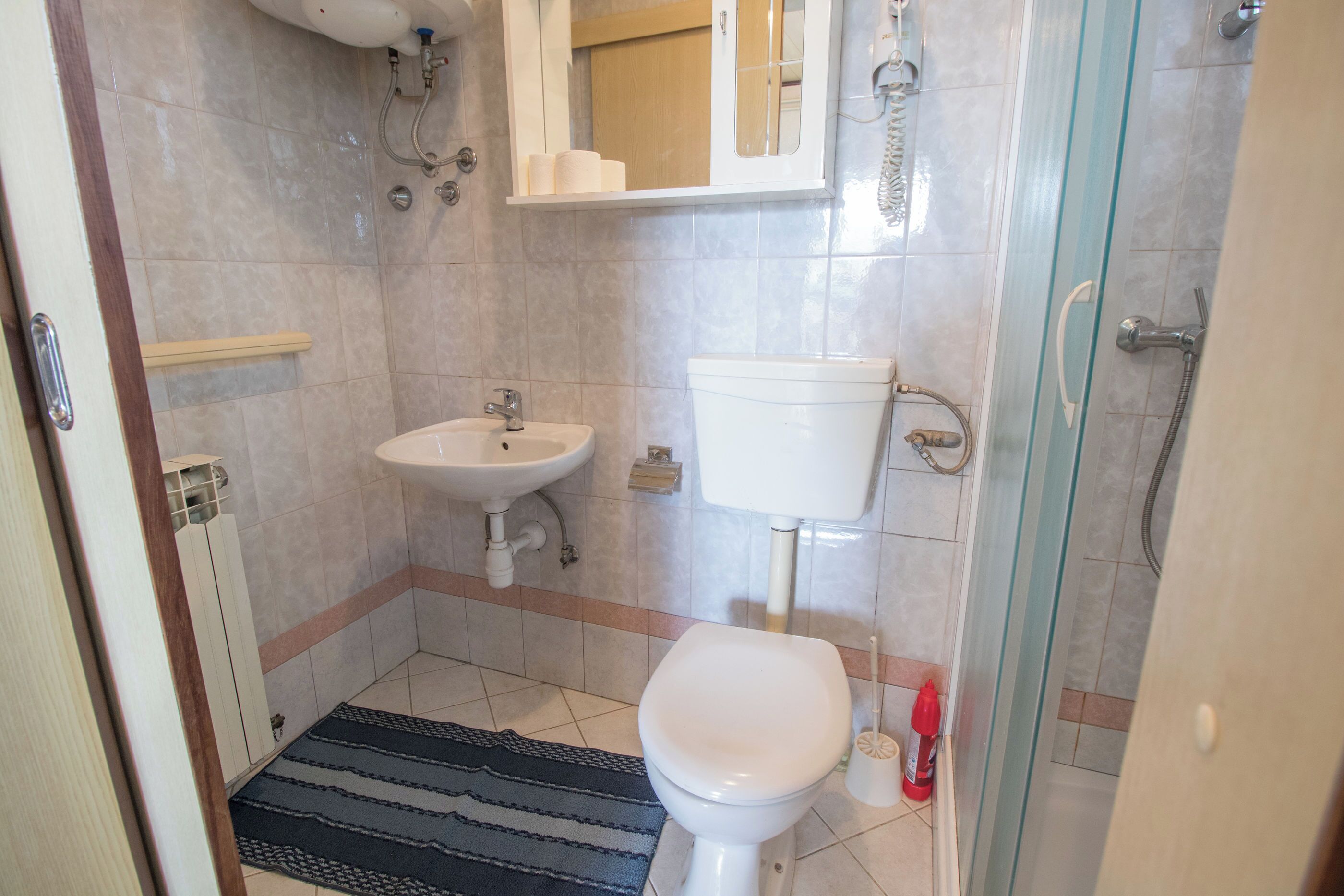 A bathroom with a toilet, sink, and shower.