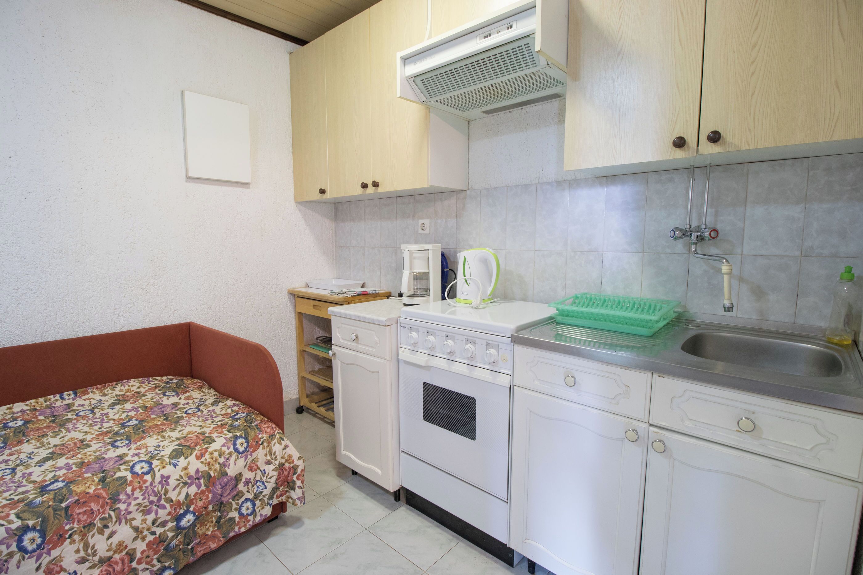 A compact kitchen with white cabinets, a built-in oven, a sink, and a small countertop.
