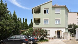 A two-story building with a green facade, a gated entrance, and a parked car in front. - Apartment Karolina (Pula)