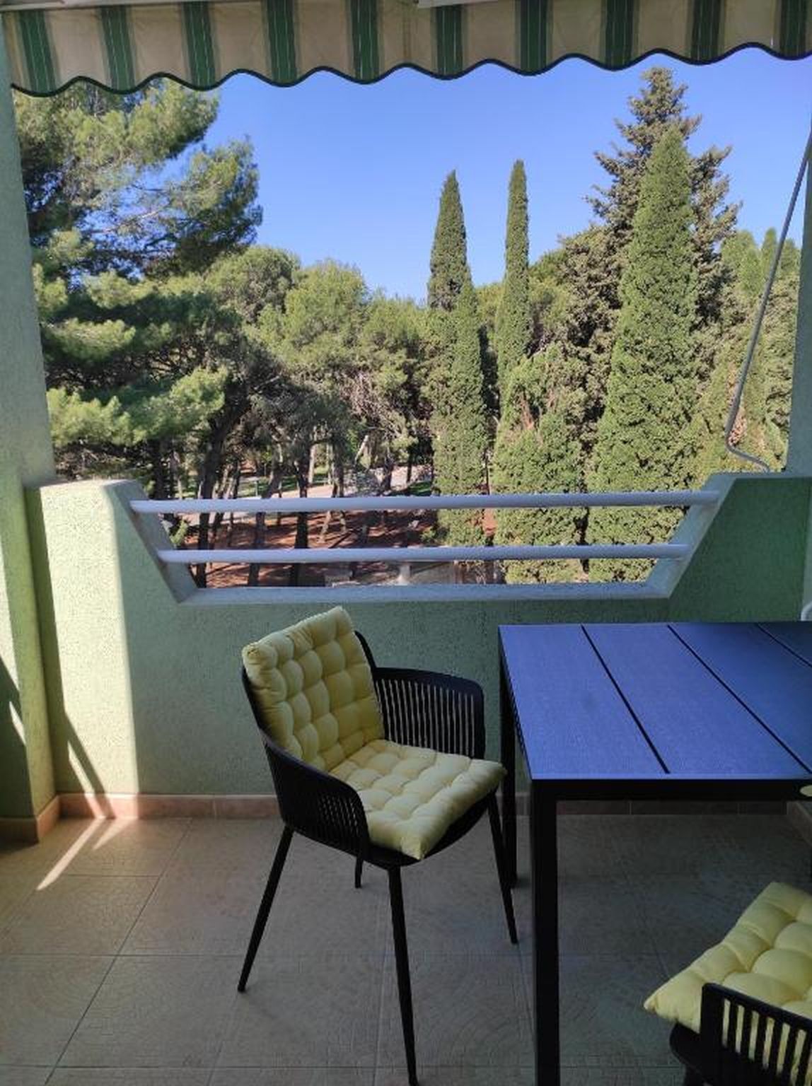Un balcon avec vue sur les arbres et une table de pique-nique.