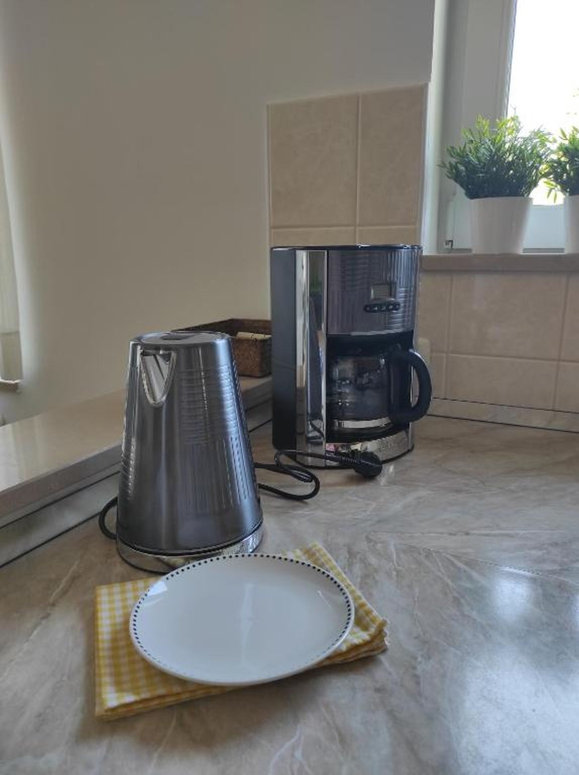 A kitchen with a coffee maker and a kettle on the counter.